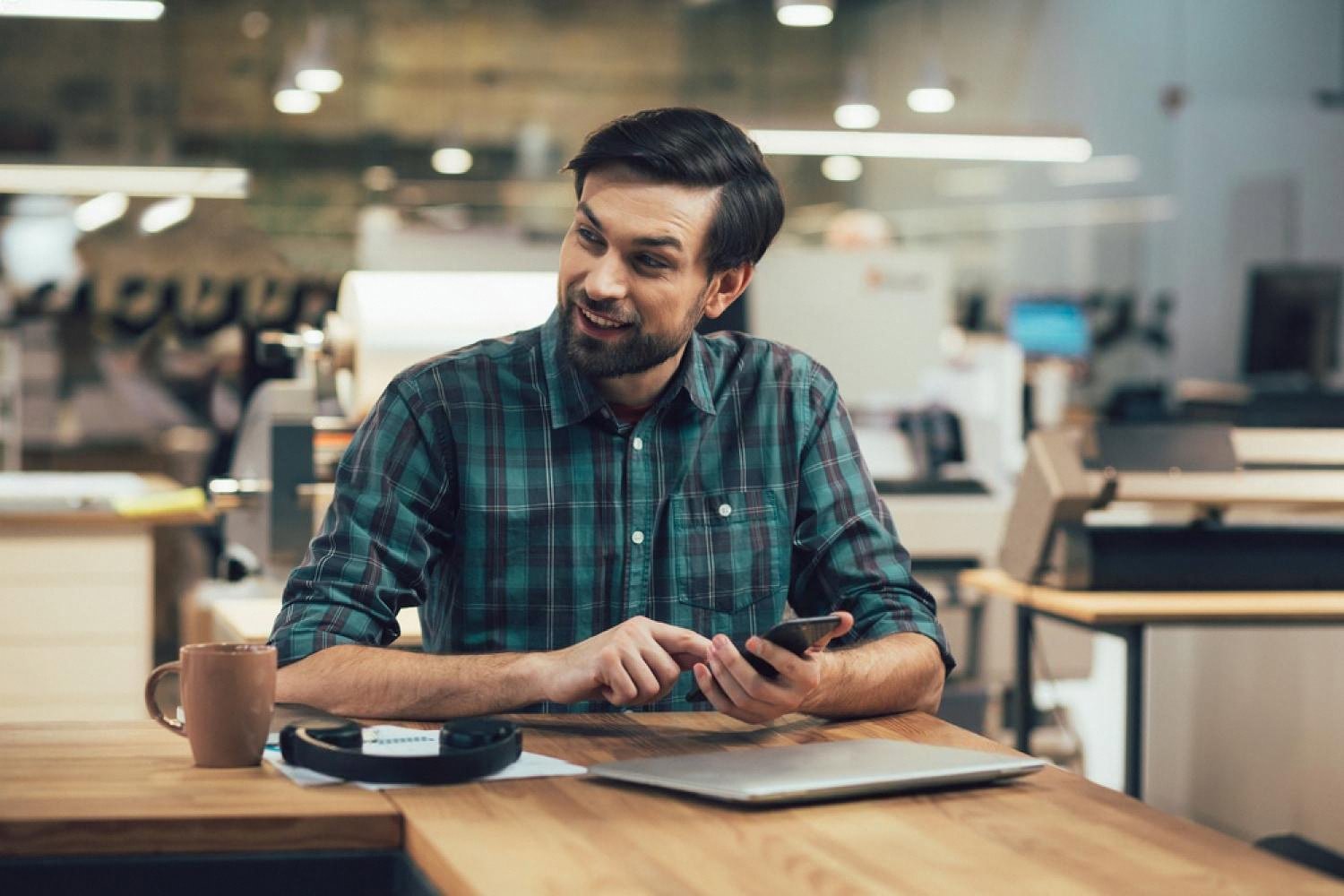 Young professional reviewing a job offer on his phone in a modern workspace